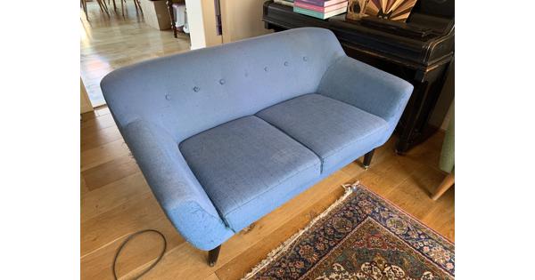 Blauwe tweezitsbank op poten retro