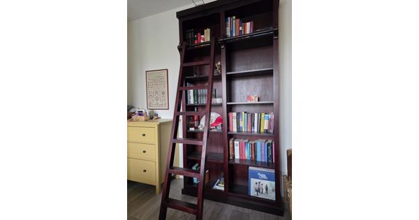 Donkerrode houten bibliotheekkast met trap