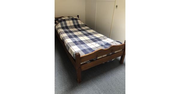 eenpersoons houten bed met matras en dekbed