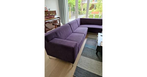 Paarse stoffen hoekbank met hocker